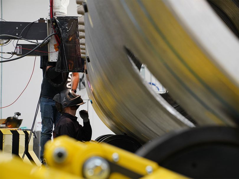 People weld a piece of rocket ship.