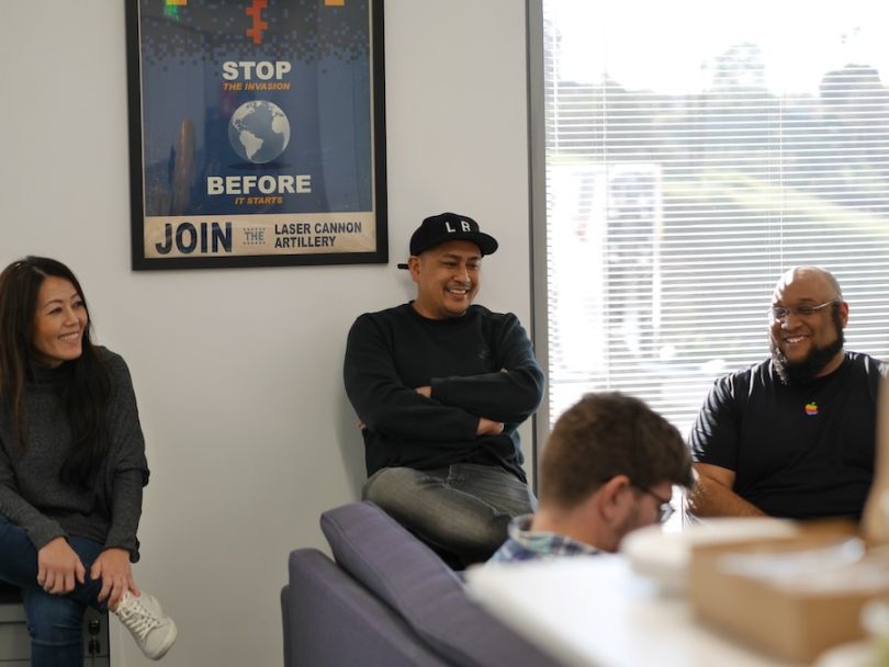 Man laughing with coworkers from his desk