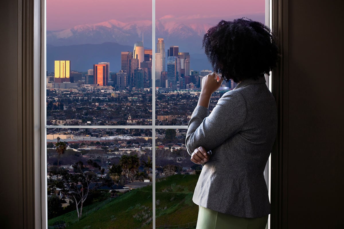 emale business woman looking out the window of an office in Los Angeles