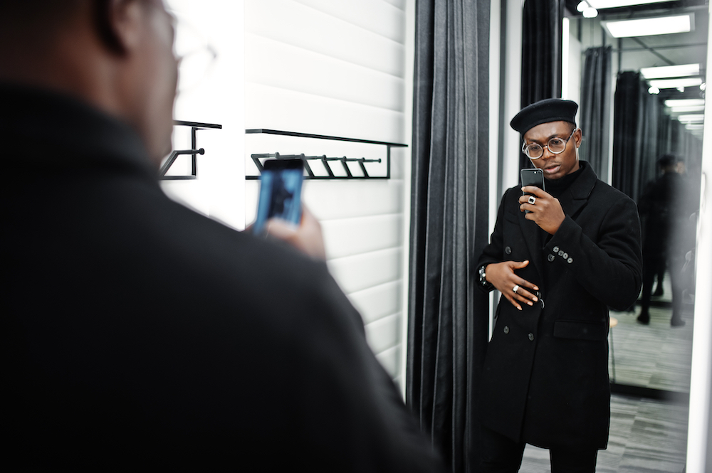 A man trying on clothes and taking a picture on his phone