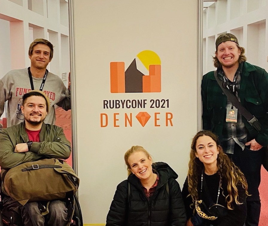 Collab coworkers posing for a photo with a sign for the Ruby Conference in Denver