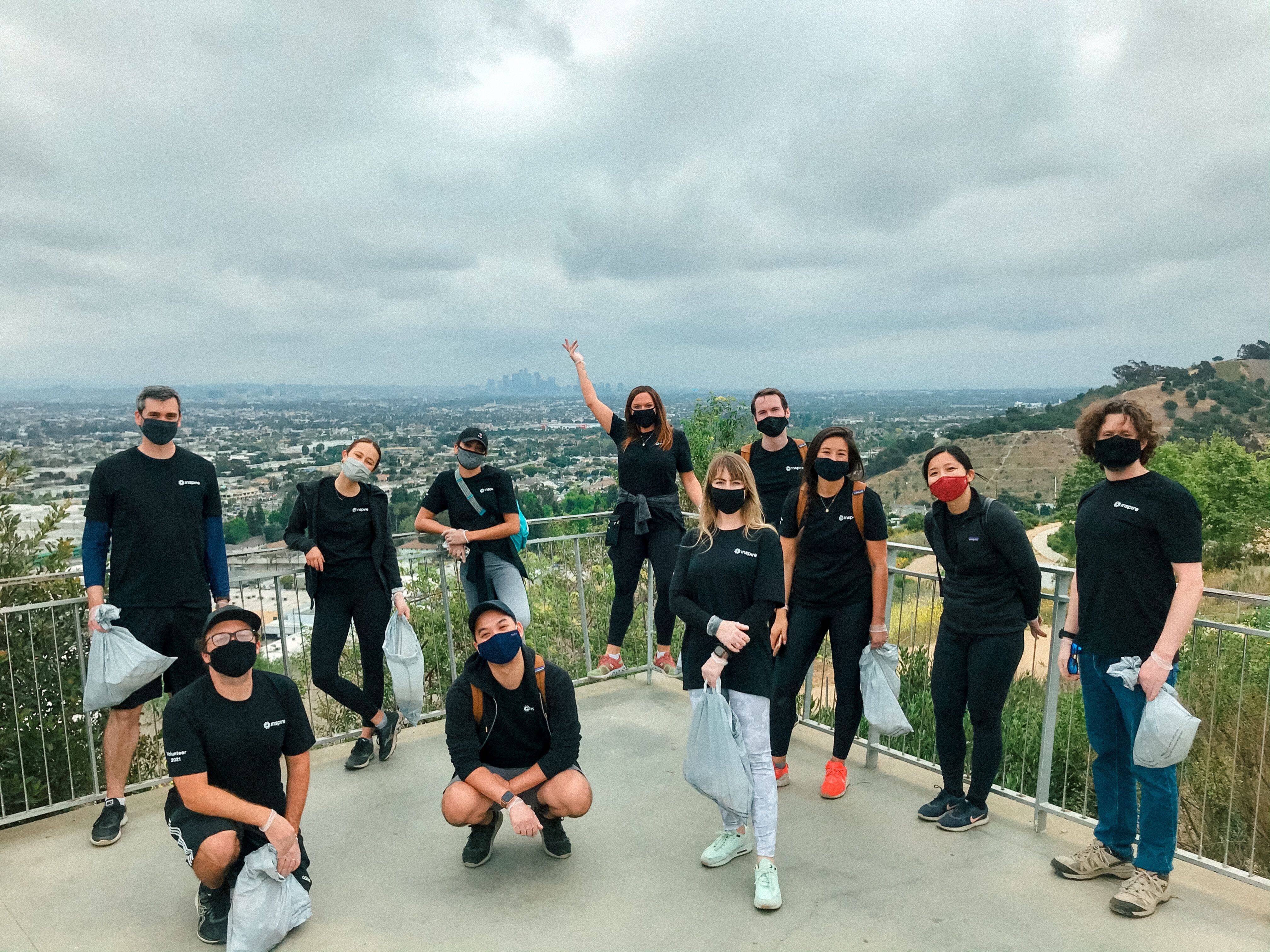 Inspire's employees, masked and wearing T-shirts with "Inspire" on the front, standing on a balcony overlooking a plain.