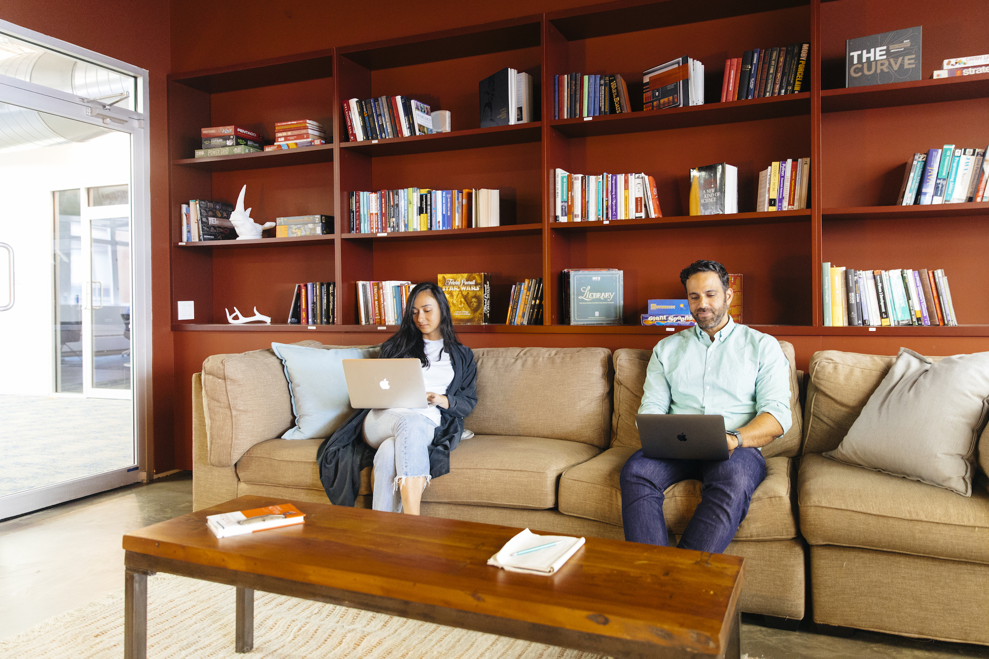 Photo of two Foursquare employees on their laptops on a couch.