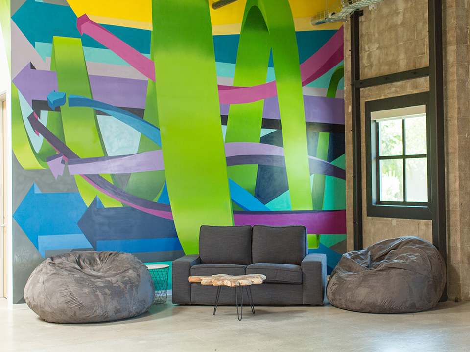 Sofa and bean bag chairs in front of an abstract mural