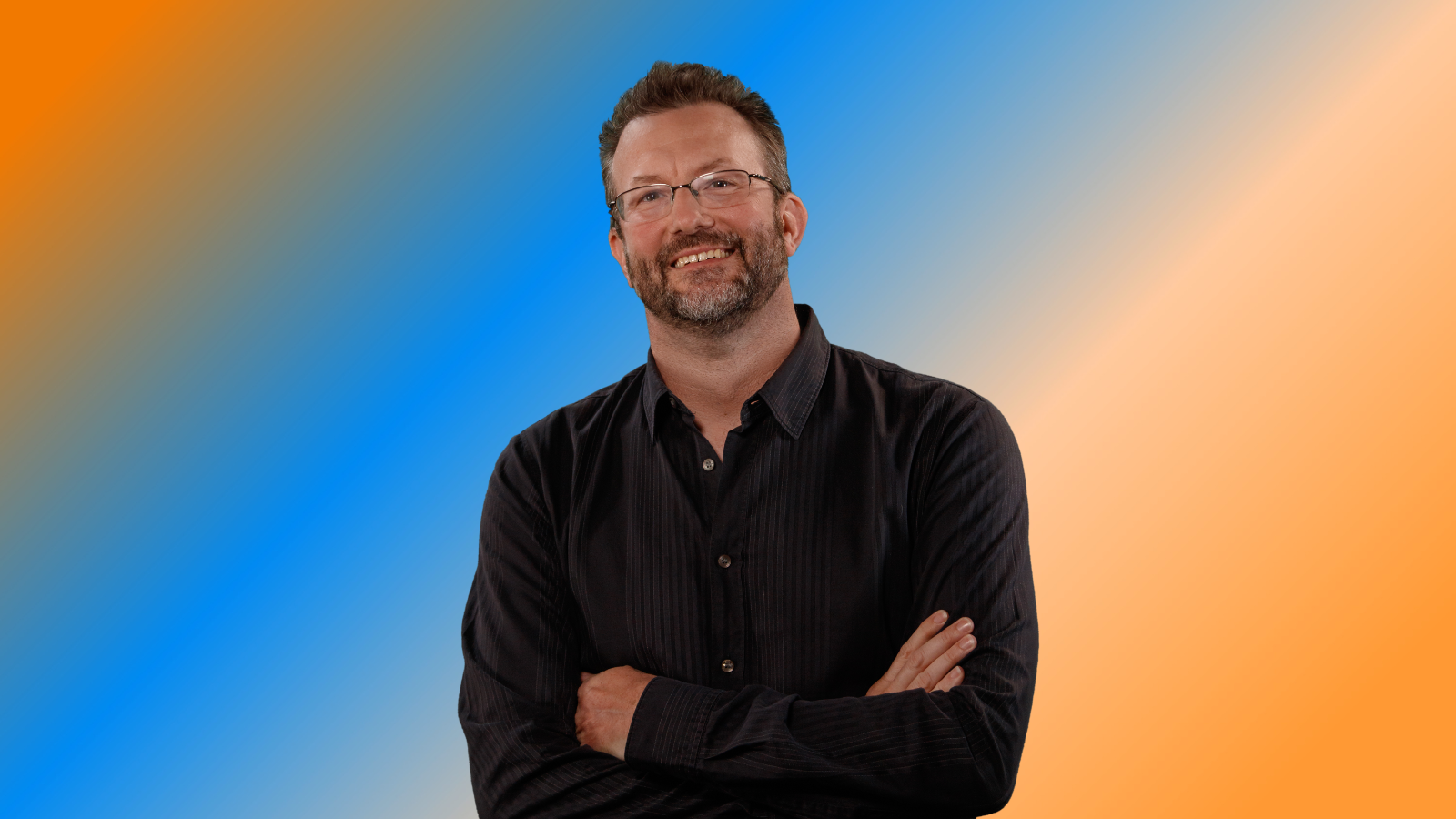 John Linden, co-founder and CEO of Mythical Games, poses for a photo in front of an orange and blue background