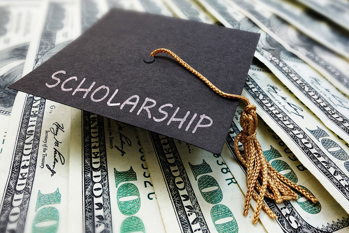 Scholarship written on a graduation cap on top of money