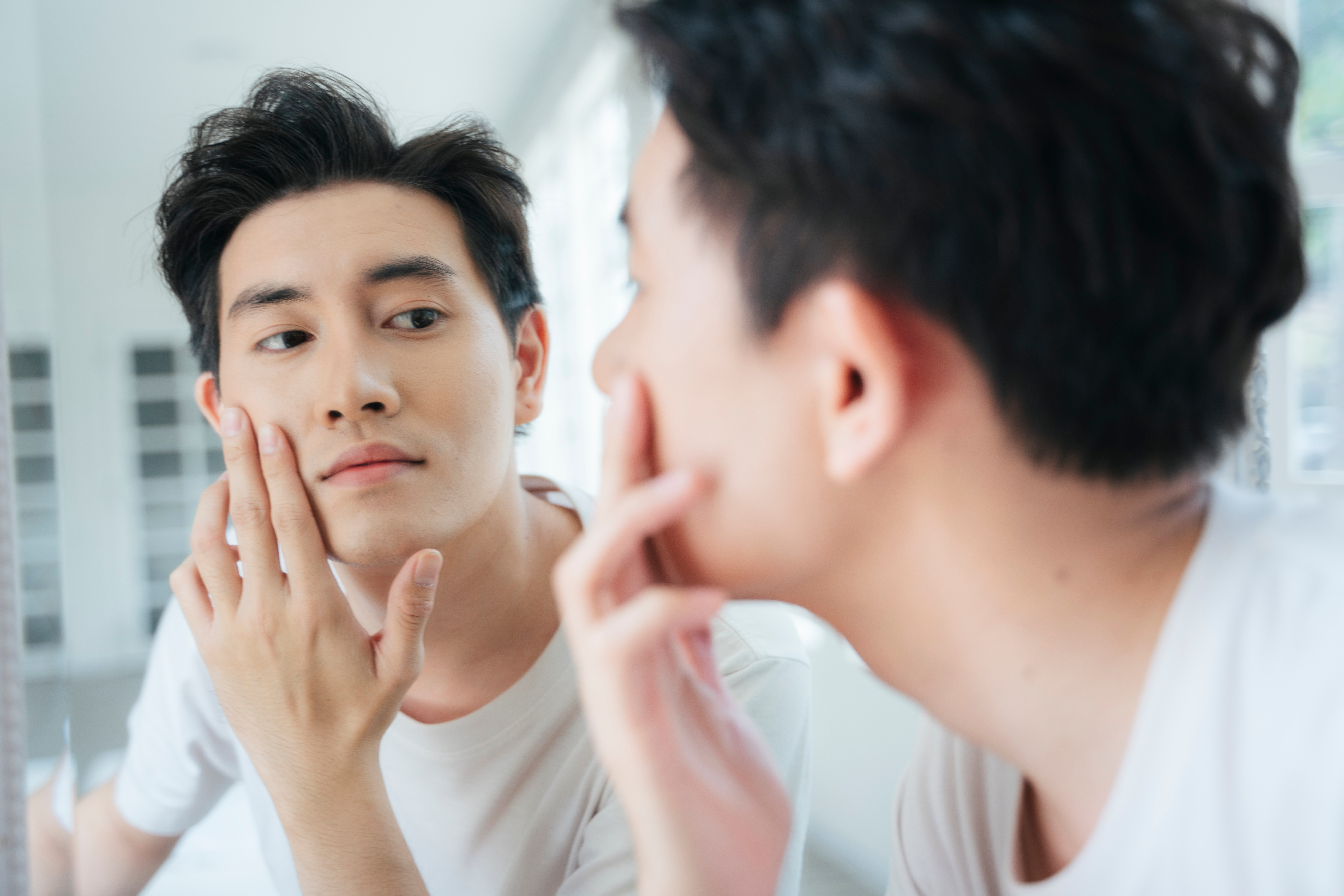 Stock photo of an Asian man looking at himself in the mirror. 
