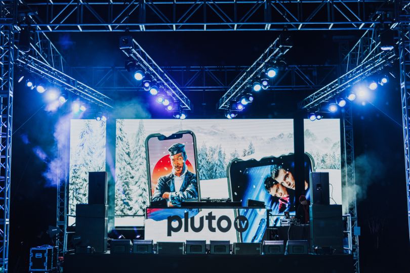 A DJ booth at an event sporting Pluto's branding.