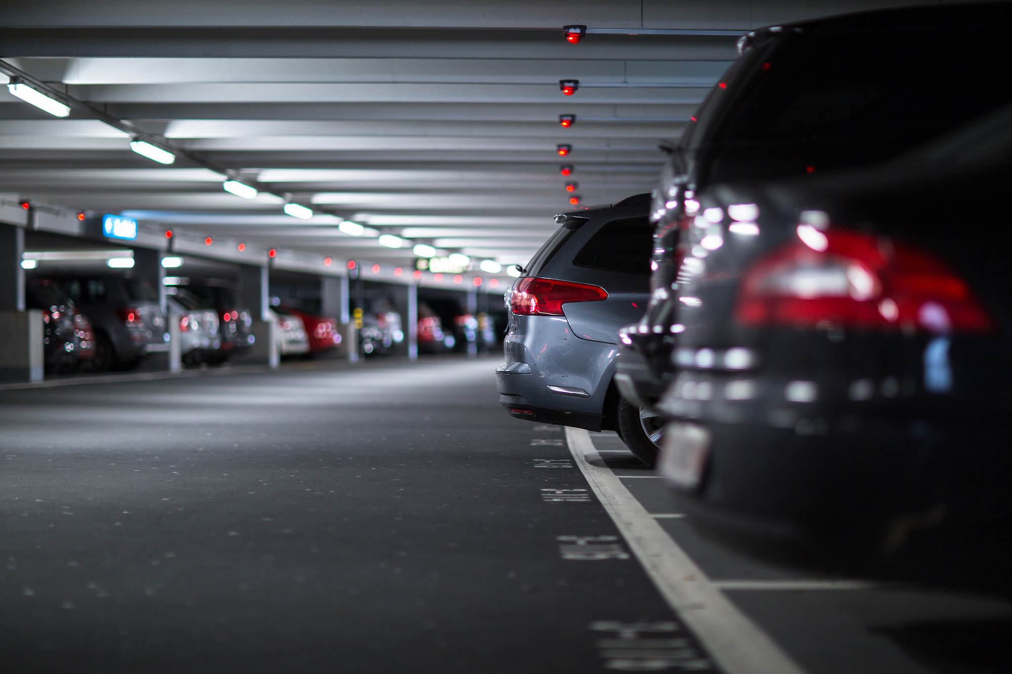 A row of cars is pictured parked in a covered garage.