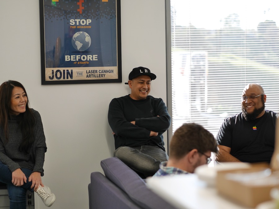 Man laughing with coworkers from his desk 