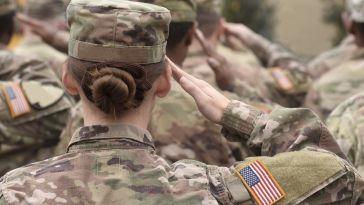 Image of a group of military service members in uniform, saluting ahead