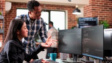 two engineers looking at a computer monitor using a software progaming application