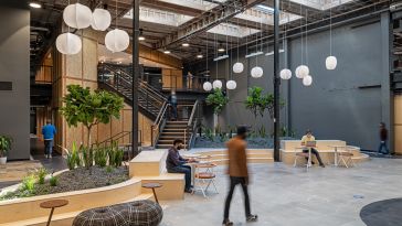 An employee walks through the open GoodRx office space filled with lanterns and plants.