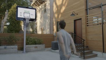 A person shooting a basketball on a huupe smart hoop.