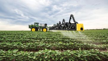 Photo of farmland with John Deere sprayer featuring See & Spray technology