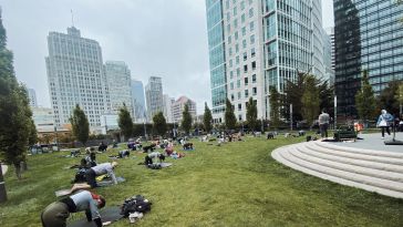 Dozens of people, including Celonis team members, enjoying yoga in the park with a cityscape background.