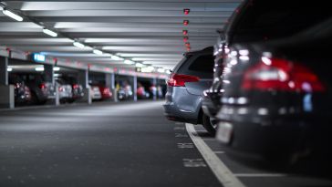 A row of cars is pictured parked in a covered garage.