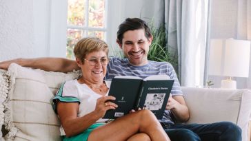 Two people sit on a couch reading a Remento Book together.